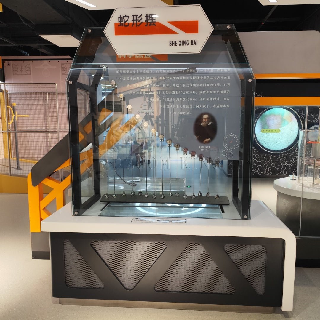 Hands-on serpentine pendulum exhibit installed in a science museum environment
