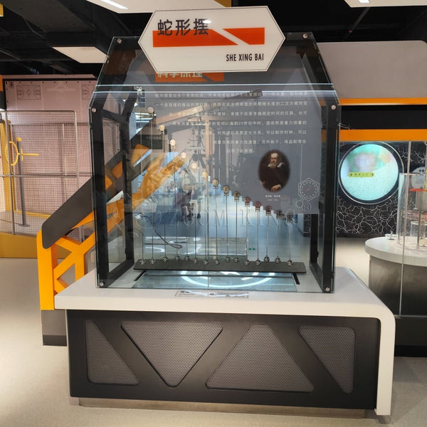 Hands-on serpentine pendulum exhibit installed in a science museum environment
